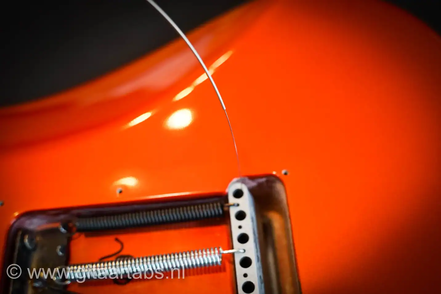 Nieuwe snaren door tremolo systeem steken